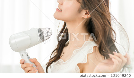 A woman blow-drying her hair with a hair dryer (hair care) A woman blow-drying her hair with a hair dryer (hair care) 131049240