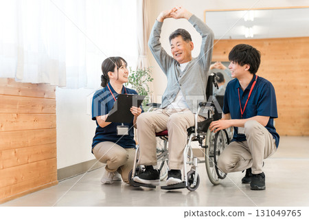 Senior/elderly man doing chair exercises, exercise and rehabilitation at a nursing facility, with physiotherapist, caregiver and trainer 131049765