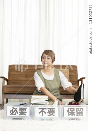 Senior woman decluttering in the living room Senior woman decluttering in the living room 131052723