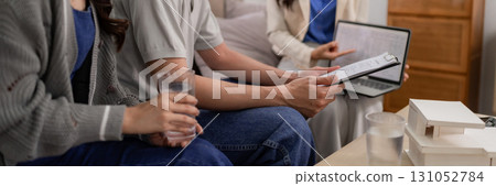 Asian adult clients meeting real estate agent at home discussing property investment plan reviewing documents architect model 131052784