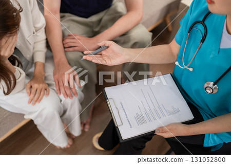 Healthcare professional conducts in home mental health consultation for an Asian couple discussing psychiatric evaluation report 131052800
