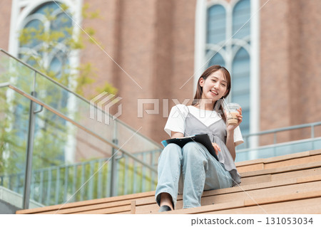 一位女大學生坐在長椅上喝咖啡 131053034