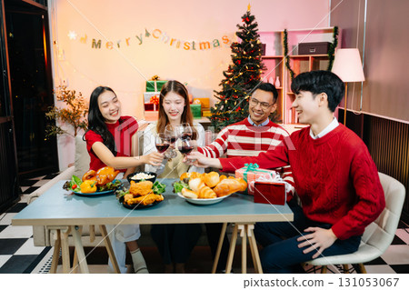 Asian friends capture the holiday spirit with gifts, laughter, and a festive Christmas dinner in a cozy, joy-filled setting 131053067