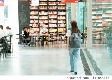 Young woman looking for a book in the library 131053113