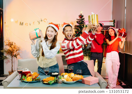 Asian friends capture the holiday spirit with gifts, laughter, and a festive Christmas dinner in a cozy, joy-filled setting Asian friends capture the holiday spirit with gifts, laughter, and a festive Christmas dinner in a cozy, joy-filled setting 131053172