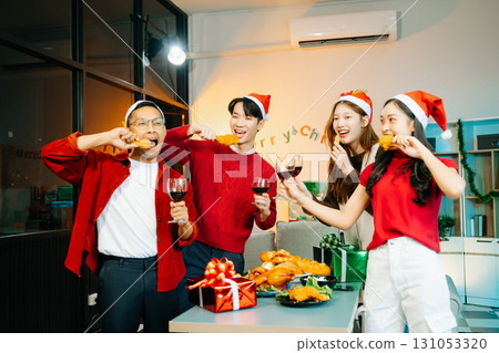 Holiday spirit with Asian friends exchanging gifts, sharing laughs, and enjoying a festive Christmas dinner 131053320
