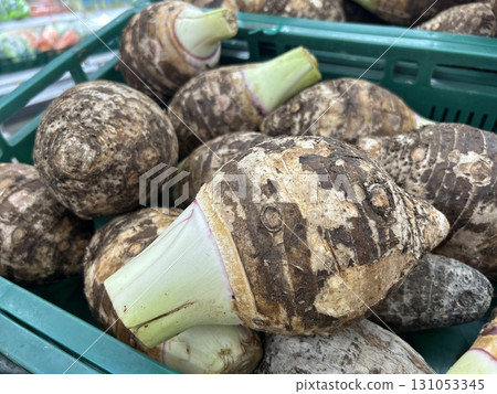 Fresh taro roots piled high in a green market crate 131053345