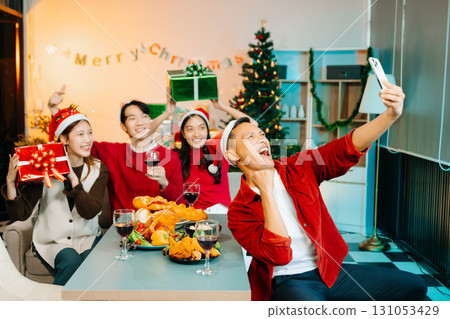 Holiday spirit with Asian friends exchanging gifts, sharing laughs, and enjoying a festive Christmas dinner 131053429