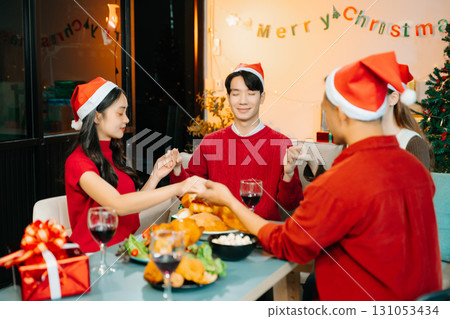 Holiday spirit with Asian friends exchanging gifts, sharing laughs, and enjoying a festive Christmas dinner 131053434