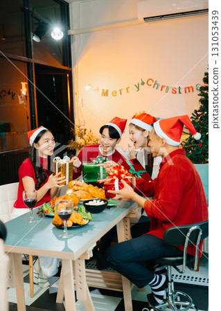 Holiday spirit with Asian friends exchanging gifts, sharing laughs, and enjoying a festive Christmas dinner 131053439