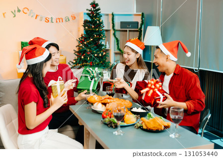 Holiday spirit with Asian friends exchanging gifts, sharing laughs, and enjoying a festive Christmas dinner 131053440
