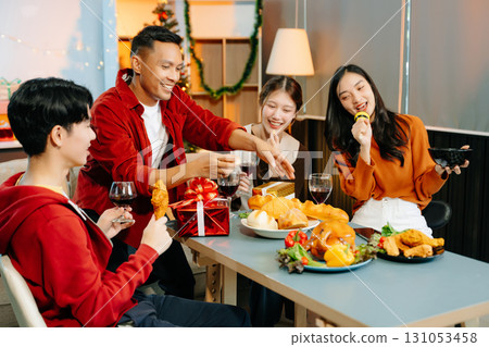 Friends celebrate Christmas with gift exchanges, festive food, and laughtera perfect scene for holiday and New Year 131053458