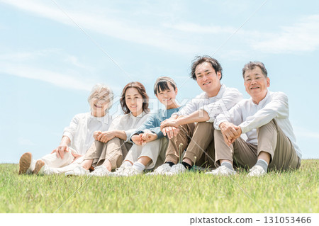 一個可以看到藍天的公園，一個坐在山上的家庭，父母和孩子，一個三代家庭（父親，母親，女兒，祖母，祖父） 131053466