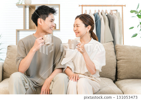 Young couple relaxing on the sofa with a hot drink Young couple relaxing on the sofa with a hot drink 131053473
