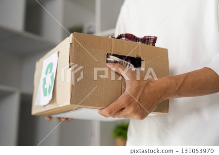 Young man carrying a box of recycled fabric, promoting eco-friendly practices in sustainable environment. Young man carrying a box of recycled fabric, promoting eco-friendly practices in sustainable environment. 131053970
