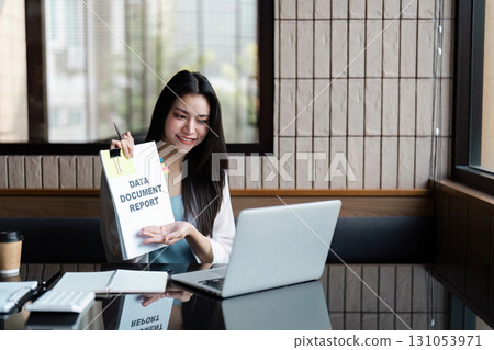Smiling businesswoman presenting a data report on a laptop, showcasing professionalism and organization. Smiling businesswoman presenting a data report on a laptop, showcasing professionalism and organization. 131053971