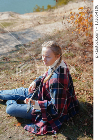 Portrait of smiling caucasian girl plays ukulele in autumnal park. Young woman plays guitar musical instrument outside in nature fall time. Audio music healing Portrait of smiling caucasian girl plays ukulele in autumnal park. Young woman plays guitar musical instrument outside in nature fall time. Audio music healing 131054106