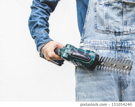 Cute woman, work clothes and hedge trimmer. Studio shot. 131054240