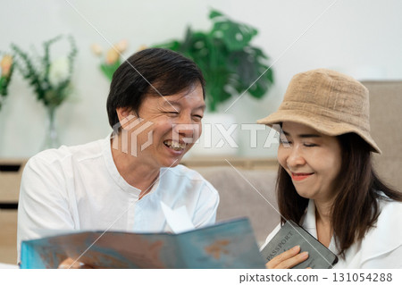 Senior couple planning travel itinerary together, sharing joy and excitement over trip details. 131054288