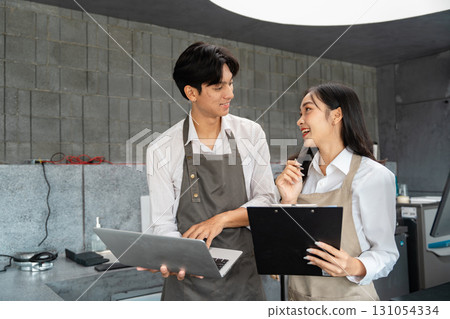 Cafe staff excitedly planning new initiatives with a laptop and clipboard Cafe staff excitedly planning new initiatives with a laptop and clipboard 131054334