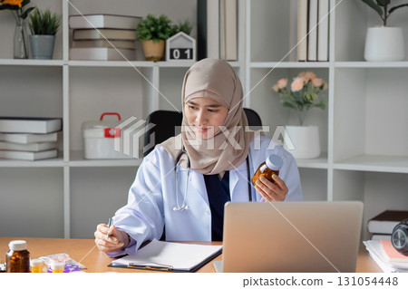Dedicated Muslim female doctor reviewing medication in her modern office, emphasizing healthcare and patient care. Dedicated Muslim female doctor reviewing medication in her modern office, emphasizing healthcare and patient care. 131054448