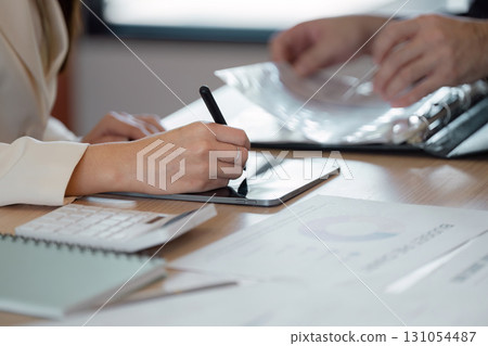 Business professionals collaborating on financial strategy with digital tools and document Business professionals collaborating on financial strategy with digital tools and document 131054487
