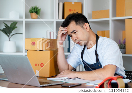 Frustrated small business owner managing orders at home office with cardboard boxes Frustrated small business owner managing orders at home office with cardboard boxes 131054522