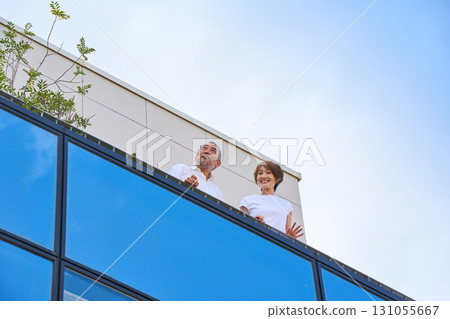 A middle-aged couple standing on the balcony. 131055667
