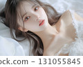 Cute young Japanese woman lying on the white sheets in bed 131055845