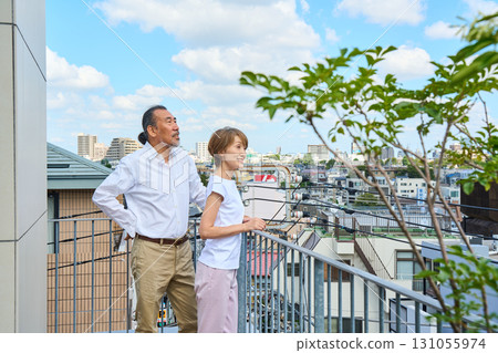 A middle-aged couple standing on the balcony. 131055974