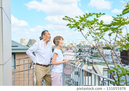 A middle-aged couple standing on the balcony. 131055976