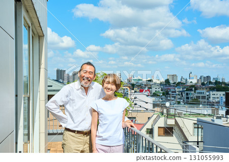 A middle-aged couple standing on the balcony. 131055993