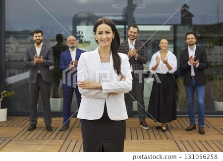 Smiling female business leader receives applause from diverse professional team 131056258