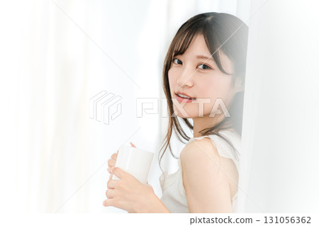 Smiling Asian woman drinking hot water, coffee, hot drink, cafe au lait, cafe latte at home in the morning Smiling Asian woman drinking hot water, coffee, hot drink, cafe au lait, cafe latte at home in the morning 131056362