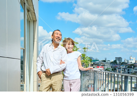 A middle-aged couple standing on the balcony. 131056399