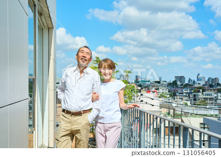 A middle-aged couple standing on the balcony. 131056405
