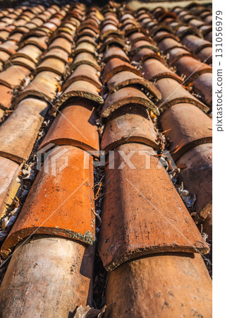 Close-up of traditional terracotta roof tiles in warm sunlight, highlighting texture and natural durability for protecting houses from heat and harsh sun. Close-up of traditional terracotta roof tiles in warm sunlight, highlighting texture and natural durability for protecting houses from heat and harsh sun. 131056979