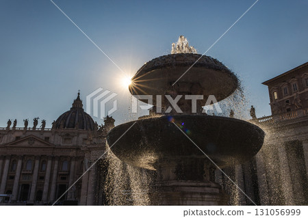 Fountain in St. Peter's Square with the sun shining dramatically through water streams, Vatican City landmark at sunrise 131056999