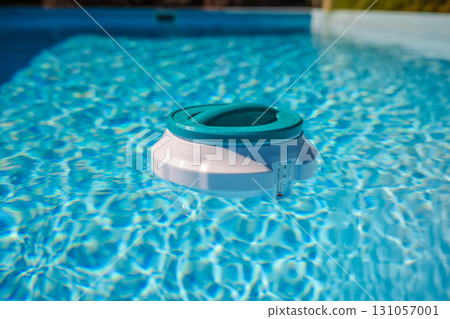Floating chlorine dispenser with thermometer drifting on pool water, ensuring effective disinfection and proper maintenance of swimming pool hygiene Floating chlorine dispenser with thermometer drifting on pool water, ensuring effective disinfection and proper maintenance of swimming pool hygiene 131057001