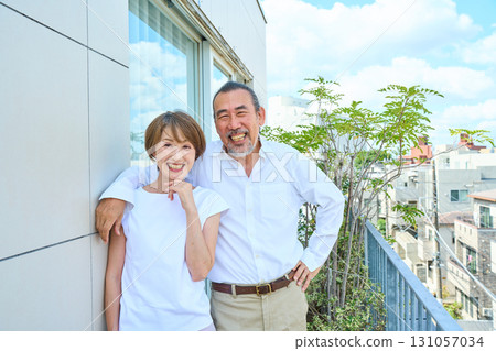 A middle-aged couple standing on the balcony. 131057034
