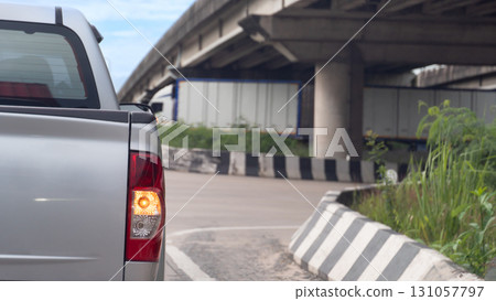 Rear side of silver pickup with turn on right turn signal. Head to the right with your directional signal on. U-turn under the concrete bridge. Blurred of truck car in the U-turn under bridge. Rear side of silver pickup with turn on right turn signal. Head to the right with your directional signal on. U-turn under the concrete bridge. Blurred of truck car in the U-turn under bridge. 131057797