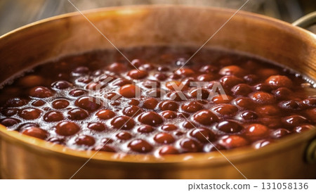 Cooking a pot of rich, red cranberry sauce on a warm stove with steam rising 131058136