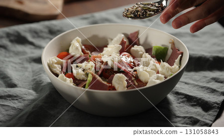 man add seeds, making salad in white bowl 131058843