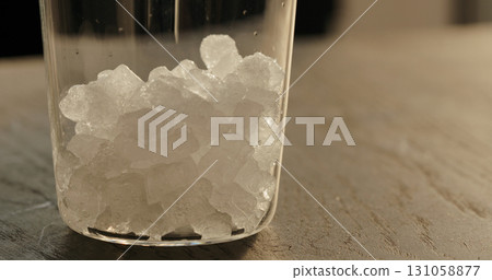 pour crushed ice in tumbler glass on oak table closeup pour crushed ice in tumbler glass on oak table closeup 131058877