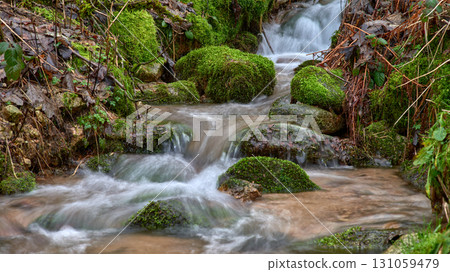 Enchanting Forest Waterfall: Cascading Mountain Stream with Autumn Foliage and Golden Sunset Light. Long Exposure Captures Silky Water Flow Over Moss Covered Rocks in Lush Green Woodland Enchanting Forest Waterfall: Cascading Mountain Stream with Autumn Foliage and Golden Sunset Light. Long Exposure Captures Silky Water Flow Over Moss Covered Rocks in Lush Green Woodland 131059479