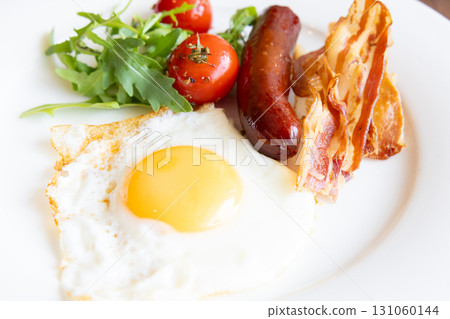 Delicious breakfast of fried eggs, bacon, sausage and grilled tomatoes 131060144