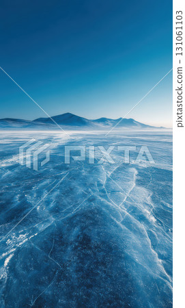 Frozen icy blue arctic landscape with vast empty ice field and distant mountain under clear sky 131061103