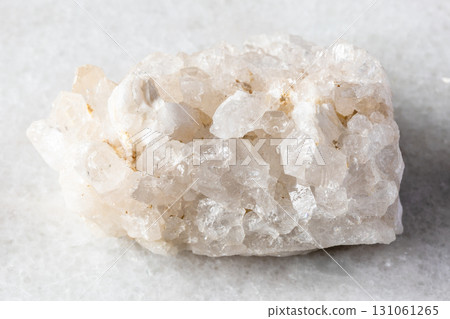 rough druse of clear quartz rock on white marble rough druse of clear quartz rock on white marble 131061265