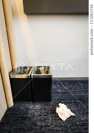 A tissue paper fell in front of the black trash can 131061556