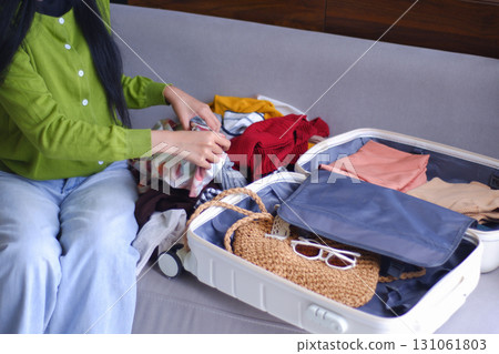 Young women folding clothes, packing luggage for holiday trip. 131061803